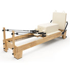 Pilates Reformer Studio Classic, telaio in rovere, rivestimento bianco latte – con sitting box e jumpboard
