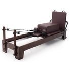 Pilates Reformer Studio Prestige, rovere finitura noce, rivestimento bordeaux – con sitting box e jumpboard