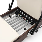Reformer Pilates pieghevole Flexi, legno espresso fumé, rivestimento bianco latte – molle e barra piedi