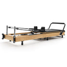 Reformer Pilates pieghevole Flexi, legno naturale, rivestimento nero – vista 3/4